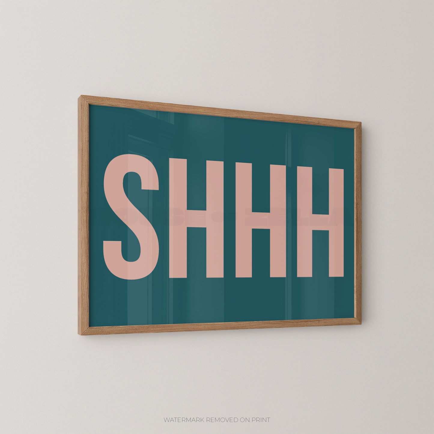 Framed typographic wall art with the word “SHHH” in large pink letters on a teal background, shown hanging on a light neutral wall.