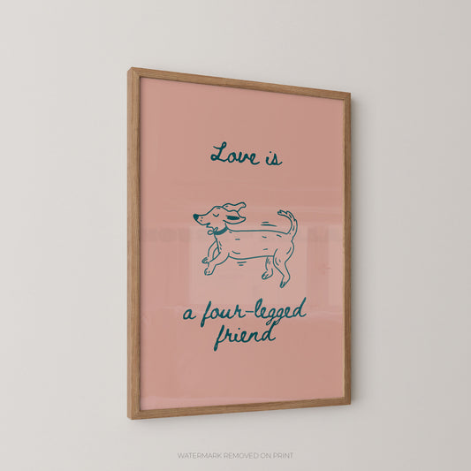 A framed art print featuring a pink background with a teal coloured line drawing of a dog and the text 'Love is a four-legged friend' in red script, displayed on a light gray wall.