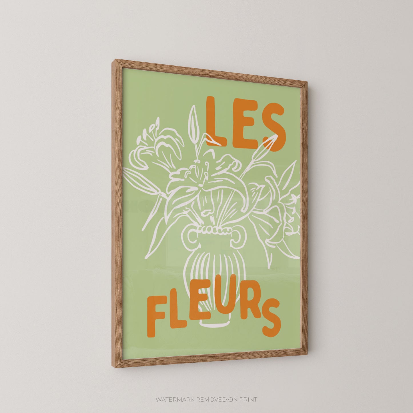 A framed art print featuring a white line drawing of flowers in a vase with the orange text 'LES FLEURS' on a light green background, displayed on a neutral light gray wall.
