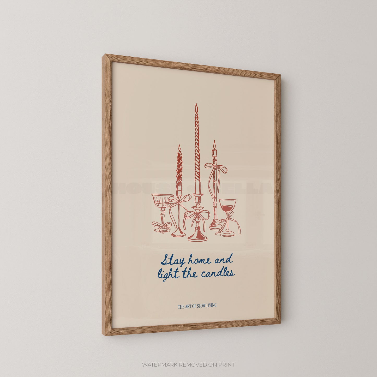 Framed wall art print featuring a minimalist illustration of candles and glassware in muted red-orange and blue text on a warm cream background, hung on a light gray wall.