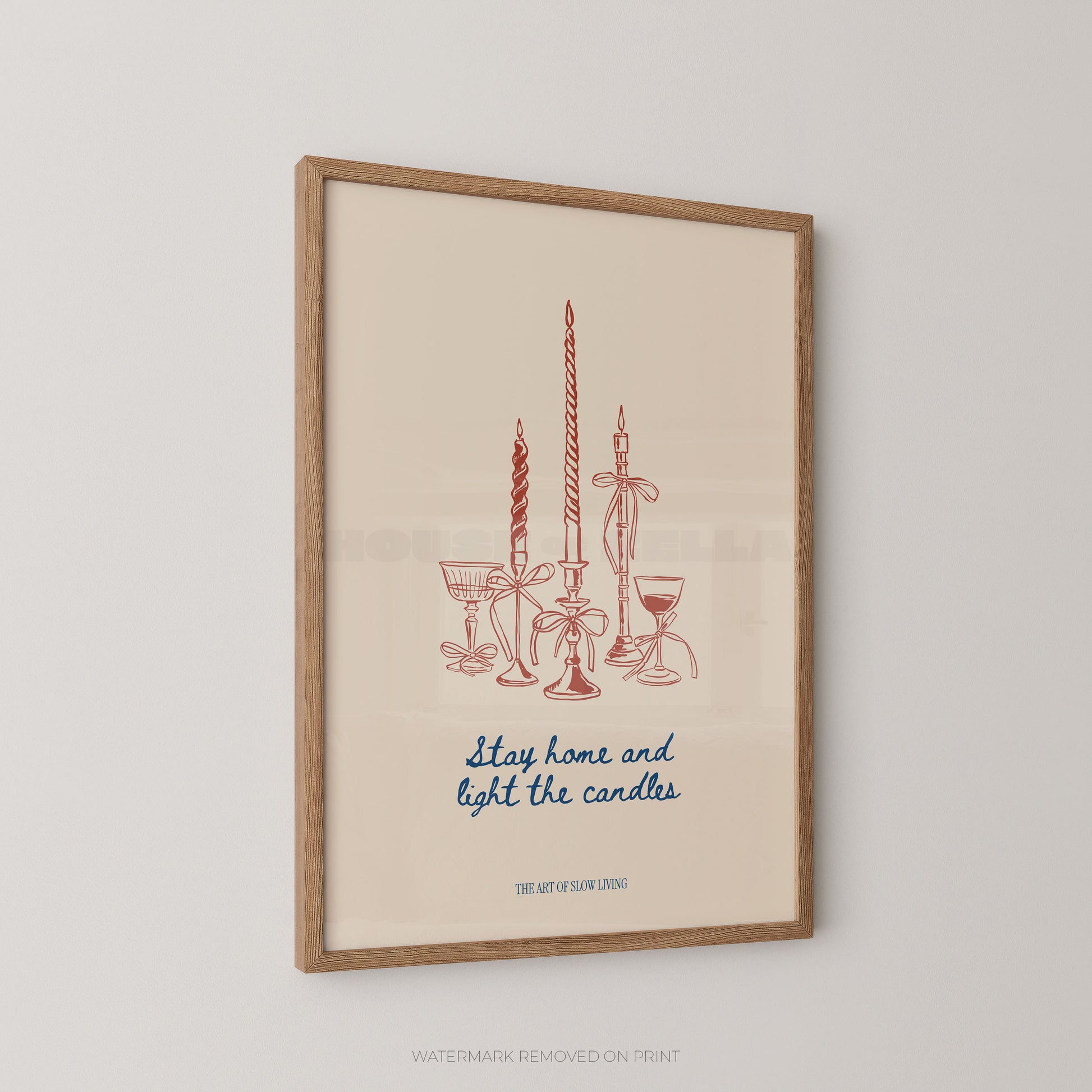 Framed wall art print featuring a minimalist illustration of candles and glassware in muted red-orange and blue text on a warm cream background, hung on a light gray wall.