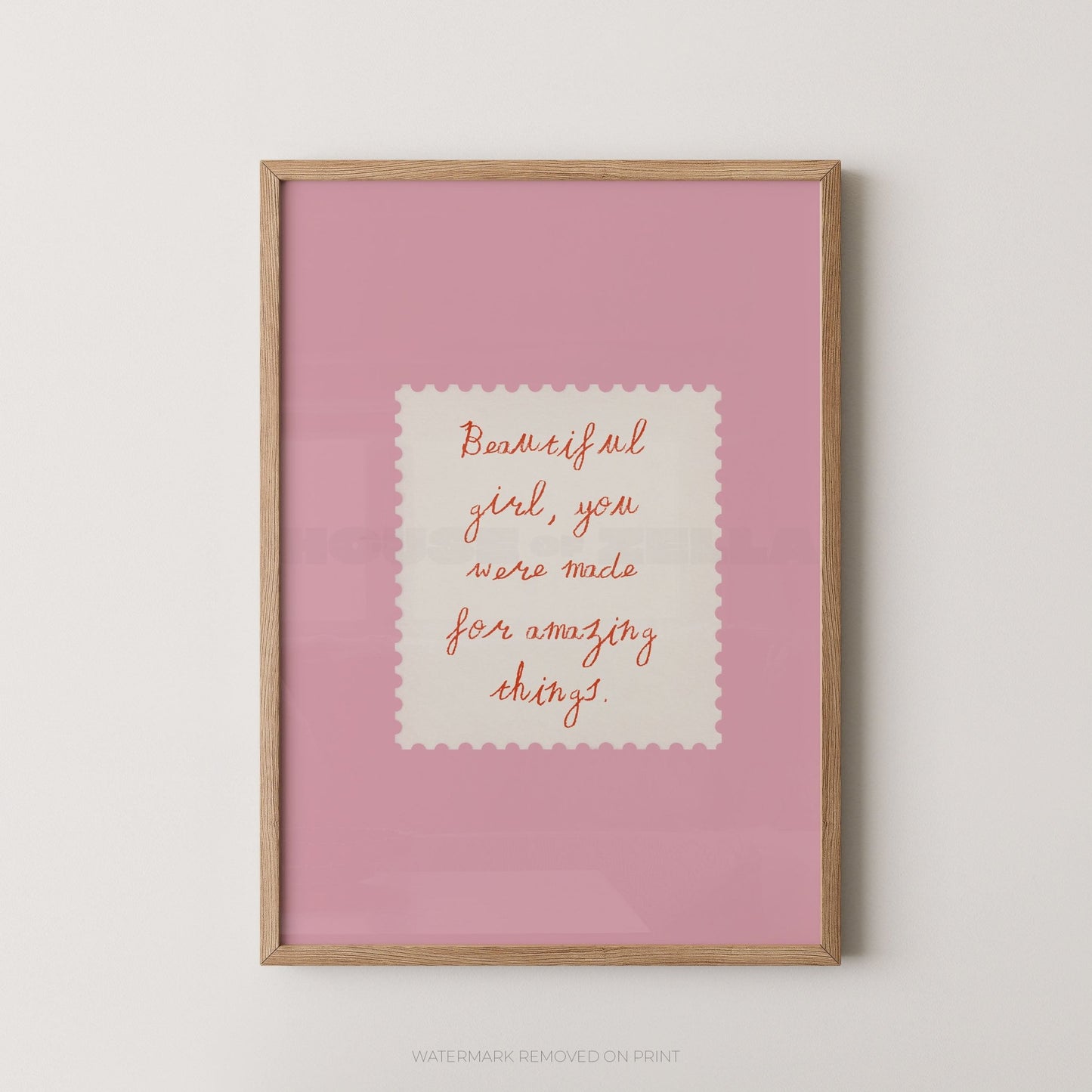 Framed pink print with motivational quote on a white wall
