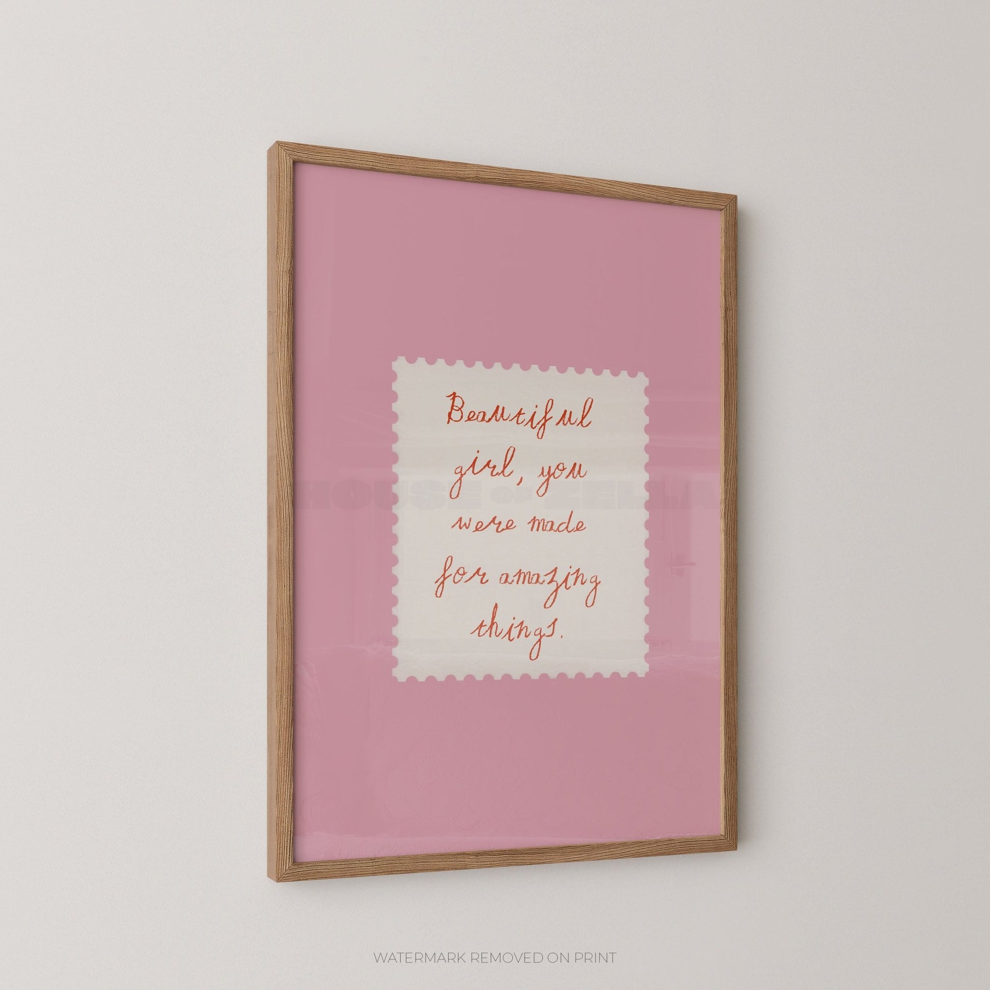 Framed pink print with motivational quote on a white wall
