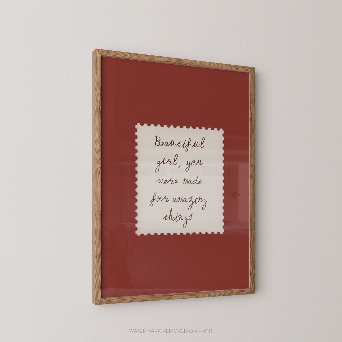 Framed text artwork with a red background and wooden frame on a light gray wall.