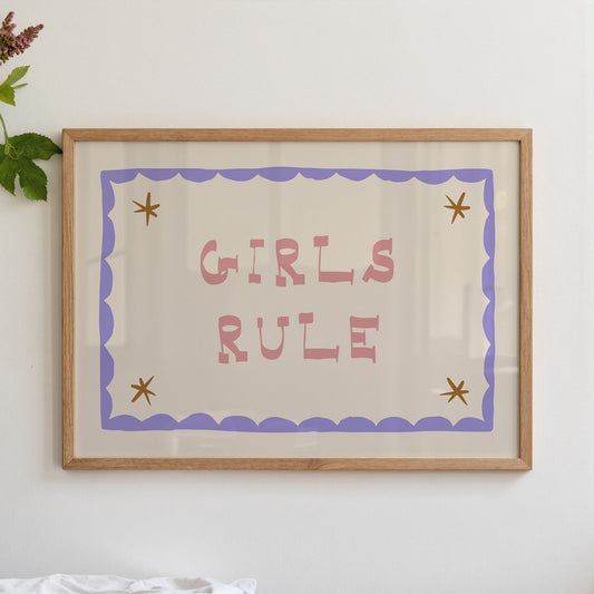 "Girls Rule children's wall art print with bold pink retro lettering on a cream background, purple scallop border with gold star details, displayed straight-on in an oak frame"


