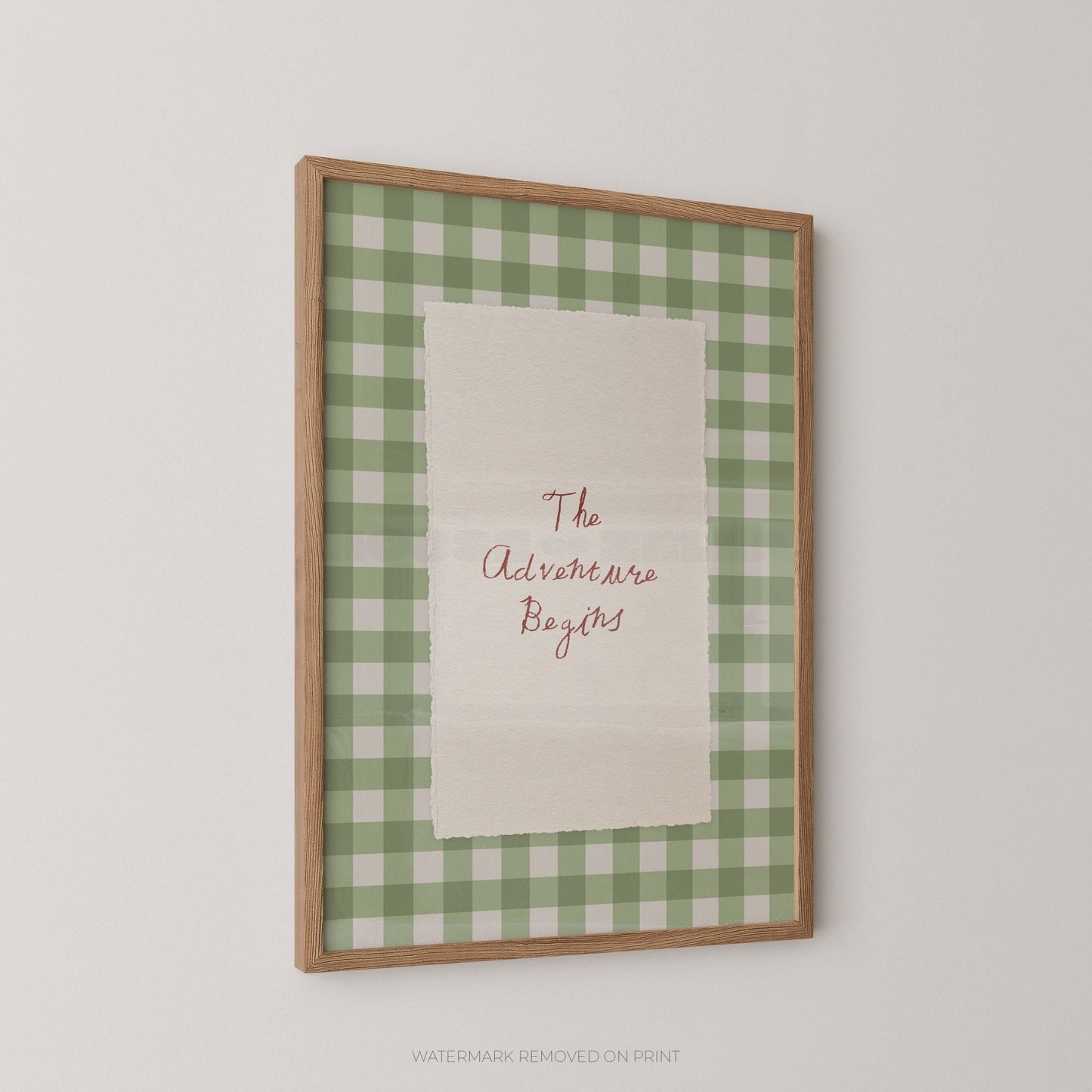 Framed print with green checkered border and 'The Adventure Begins' text on a white background