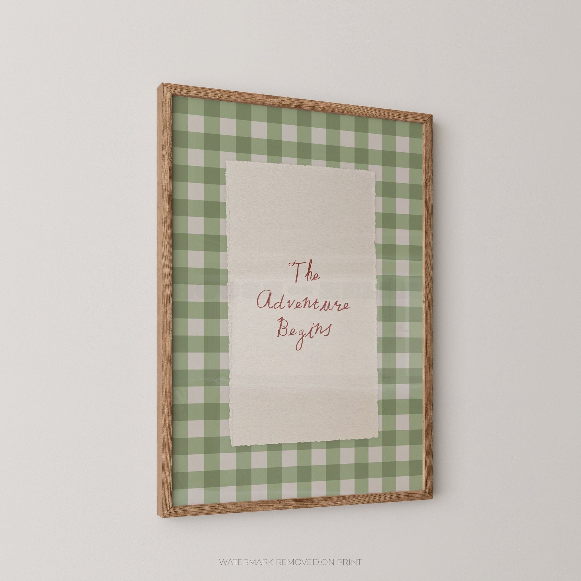 Framed print with green checkered border and 'The Adventure Begins' text on a white background